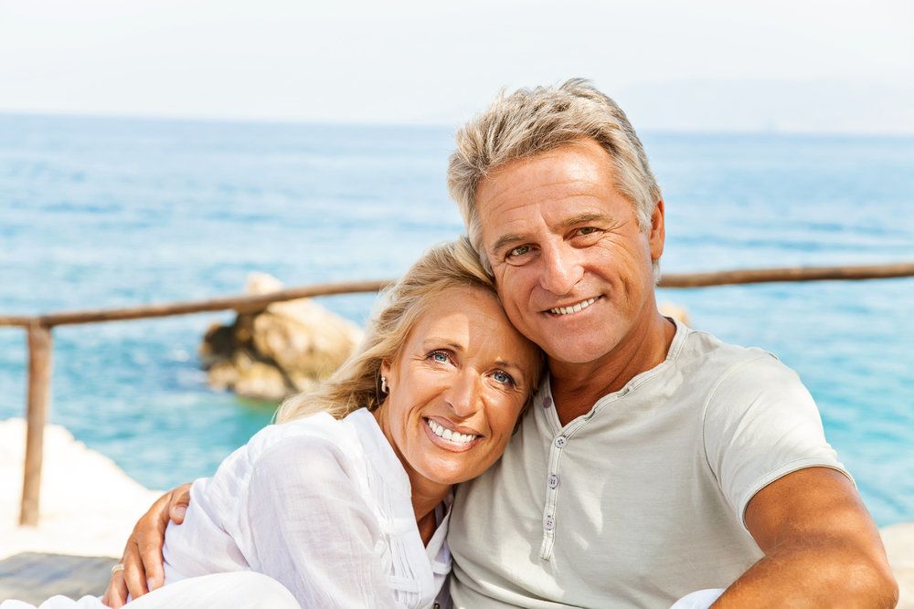 Tan smiling couple in front of the ocean