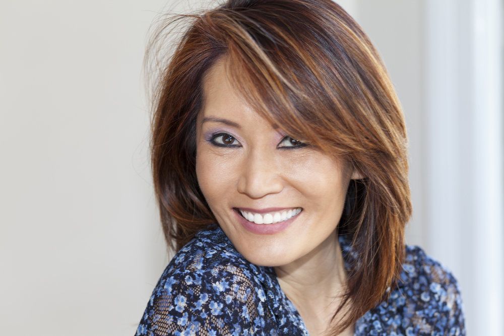 Smiling woman in flowered blue shirt looking coyly over shoulder