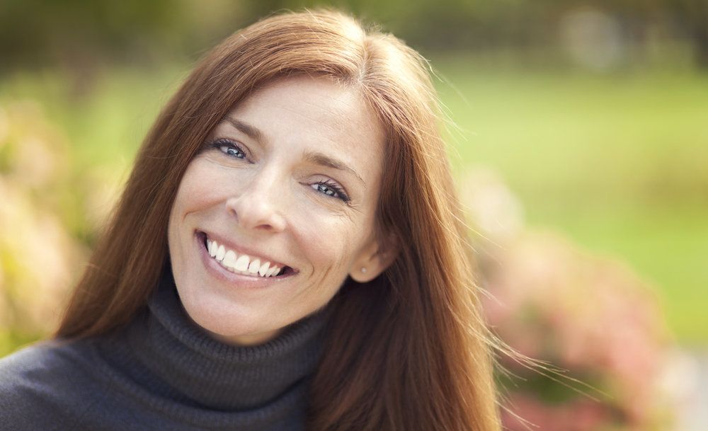 Smiling red-headed woman wearing gray turtleneck