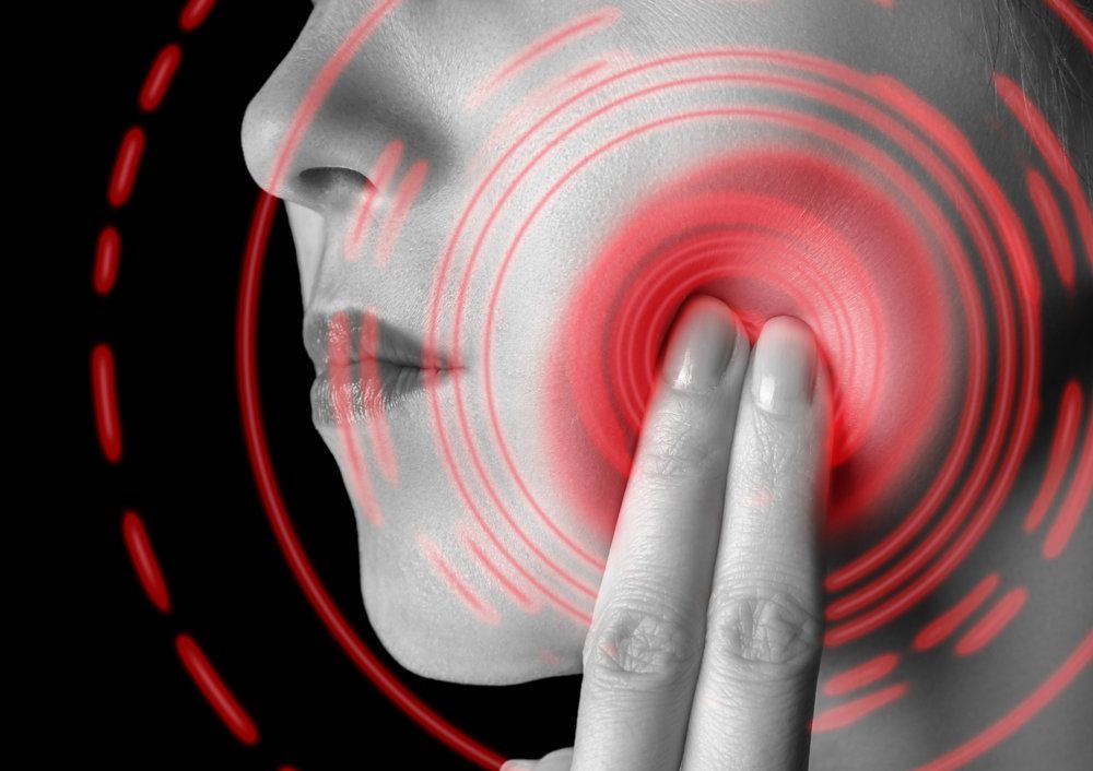 Woman holding finger to jaw with illustrated pain radiating from joint
