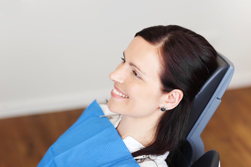 Brunette woman smiling while sitting in a dental chair